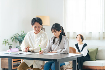 勉強を教わる女の子と見守る母親