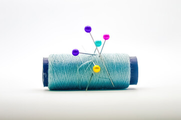 a roll of sewing thread pierced by a pin isolated on white background with copy space