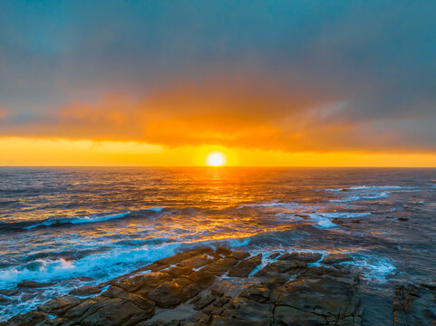 Cloudy sunrise over the ocean with rock platform