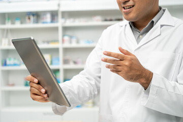 Professional Pharmacist man in uniform holding medicine bottle talks to patient via online video conferencing advice to customers standing near drug shelves counter. Pharmacist inventory medicine