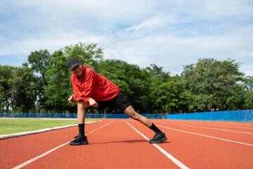 Obraz premium Young asian man wearing sportswear running outdoor. Portraits of Indian man stretching leg before running on the running track at sport stadium. Training athlete work out at outdoor concept.