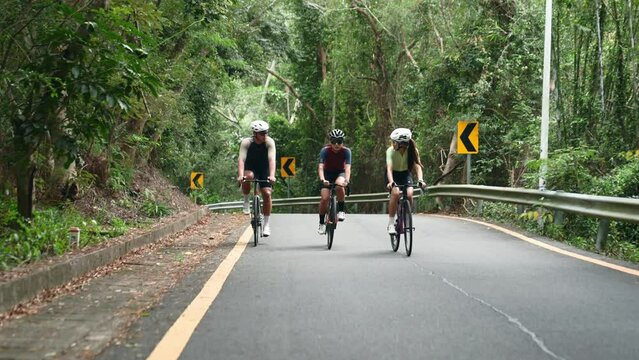 three young asian cyclists riding bikes outdoors on rural road