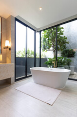 Luxury bathroom with white bathtub by the window, concept in a modern house