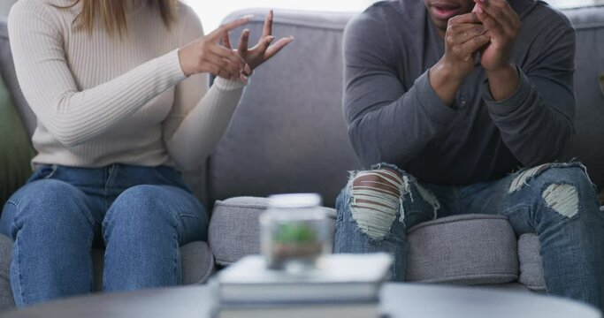 Frustrated couple, hands and argument on sofa in conflict, fight or disagreement together at home. Closeup of man and woman in discussion on problems, cheating affair or relationship in living room