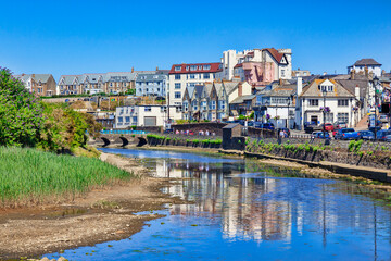 Bude, Cornwall, UK - Homes and businesses in the seaside town, reflected in the River Neet, on a hot summer day.