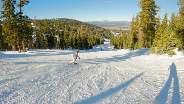 Male snowboarder rides down an intermediate hill