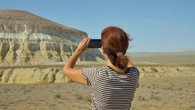 Tourist woman making photo of Sharkala mountain in Kazakhstan. 4k video footage UHD 3840x2160
