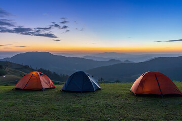 Group of adventurer tents during overnight camping site at the beautiful scenic sunset view point over layer of mountain for outdoor adventure vacation travel concept