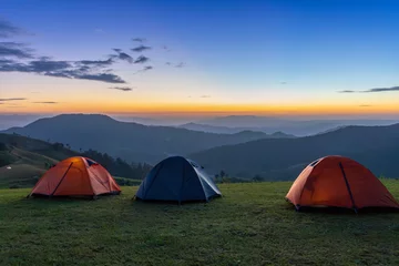 Foto op Plexiglas Group of adventurer tents during overnight camping site at the beautiful scenic sunset view point over layer of mountain for outdoor adventure vacation travel concept © Akarawut