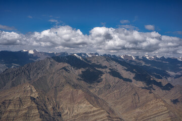 Eye Level view of rainbow colored mountain with patches of cloud shadow and snow on the mountains