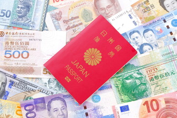 日本のパスポート（一般旅券10年用赤色）と、さまざまな国の通貨の紙幣で、海外旅行のイメージ
