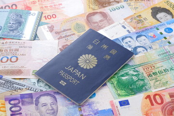 日本のパスポート（一般旅券5年用紺色）と、さまざまな国の通貨の紙幣で、海外旅行のイメージ