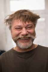 The mans face, with a beard and moustache, shows a happy smile with his eyes closed. His jawline reveals wrinkles, indicating a pleased expression