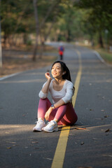 A young woman sits on the road to rest after jogging.