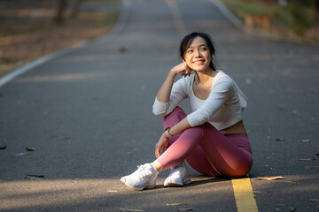 Fototapeta premium A young woman sits on the road to rest after jogging.