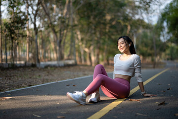 A young woman sits on the road to rest after jogging.