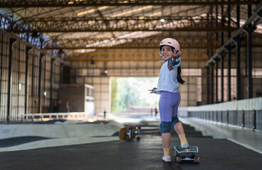 surfskate by asian child skater or kid girl smile start riding surf skate at pump track or fun playing skateboard in skate park by extreme sports surfing to wearing helmet wrist knee guard body safety