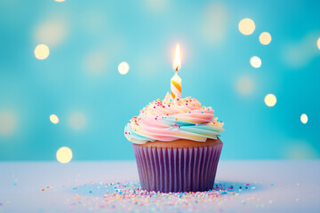 Single cupcake with colorful frosting and burning birthday candle in front of blue background