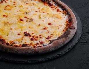 black pizza with cheese on stone