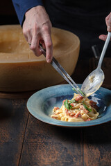 The chef serves a plate of tagliatelle pasta with sun-dried tomatoes, basil and parmesan cheese. Alfredo Italian pasta