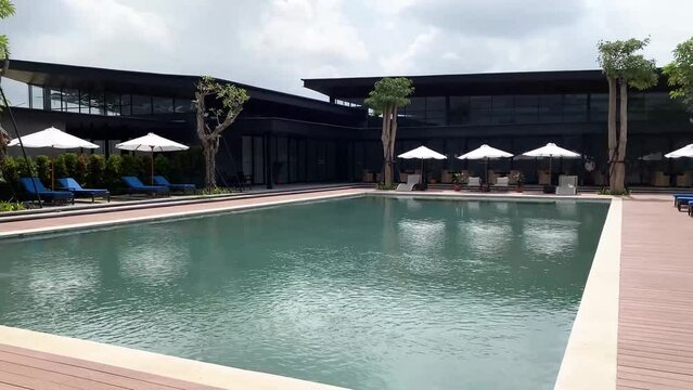 Outdoor swimming pool with club house building on sunny cloudy day. Swimming pool on property real estate show units. 