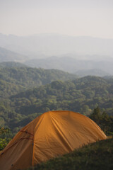 landscape and travel concept with orange camping tent with layer of mountain