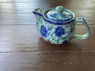 chinese blue flower-style teapot on antique dark brown table with copy space at the bottom of the frame