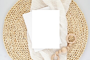 Vertical blank card mockup for baby shower invitation, greeting card design, 5x7 size, flat lay on wicker mat.