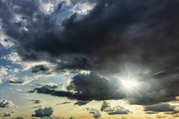 Dramatic sky with dark clouds and bright sunlight breaking through for nature background