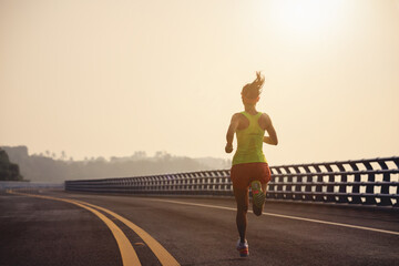 Fototapeta na wymiar Fitness woman runner running on seaside bridge