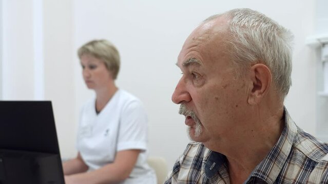 Portrait of an old man patient talking to doctor with female nurse behind. Clip. Concept of public health services.