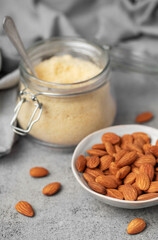Fresh almond flour in a  glass jar and almonds