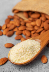 Fresh almond flour in a  wooden spoon and almonds