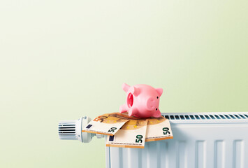 empty piggy bank upside down on euro bank notes on radiator, heating and energy prices, green...