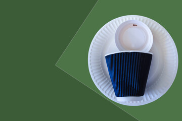 A set of disposable paper round plates and cup on green background. Eco friendly. 