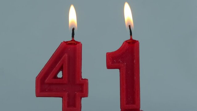 close up on timelapse melting a red number forty one birthday candle on a white background.
