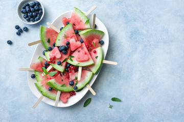 Watermelon popsicle yummy with blueberries and mint on a blue background. Copy space, top view.