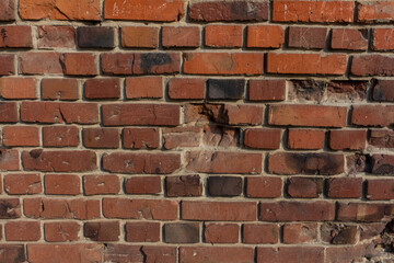 Close-up view of old molded red brick wall covered with craters from military shells, bullets, cracks and scratches. Copy space for your text and decorations. Soft focus. Aftermath of the war theme. - obrazy, fototapety, plakaty