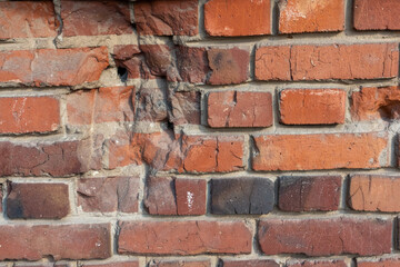 Close-up view of old molded red brick wall covered with craters from military shells, bullets, cracks and scratches. Copy space for your text and decorations. Soft focus. Aftermath of the war theme.