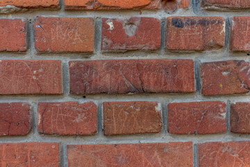 Obraz premium Weathered dark brick background. Close-up view of old molded red brick wall covered with cracks and scratches. Copy space for your text and decorations. Demolition theme.