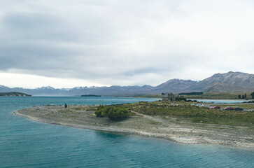 A panoramic view of Lake Tekapo, New Zealand, featuring the scene of a milky turquoise lake and the historic church landmark.