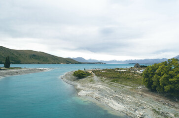 A panoramic view of Lake Tekapo, New Zealand, featuring the scene of a milky turquoise lake and the historic church landmark.