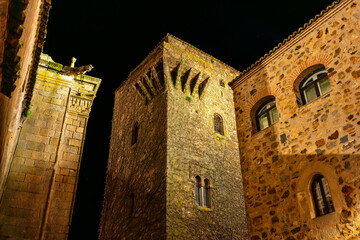 Stone towers of monumental buildings at night in the medieval town of Caceres, Extremadura.