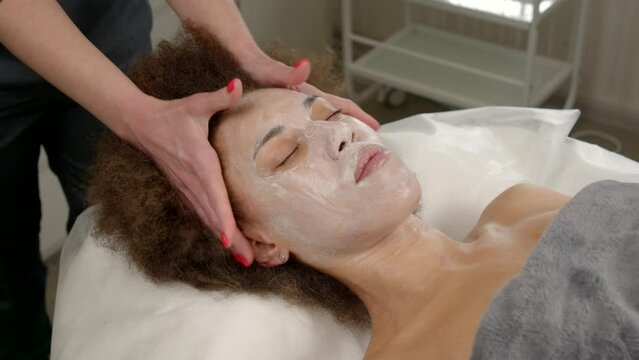 Skillful Female Masseuse Doing Beauty Beauty And Spa Procedure, Giving Scalp Massage To Relaxed Pretty African American Woman, Improving Blood Circulation And Hair Growth Stimulation Indoors.