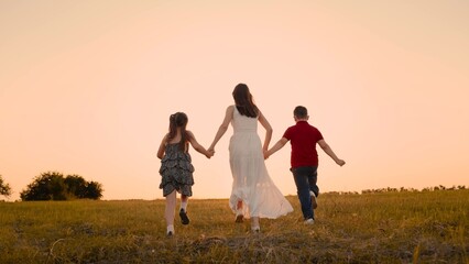 mother runs into sunset holding her son daughter hand, happy family running, boy girl, chasing...