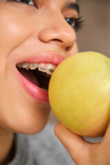 Close up of female teenager with braces eating an apple.