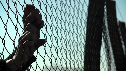 hopeful woman's hands clinging to the border fence: dreaming of freedom, peace