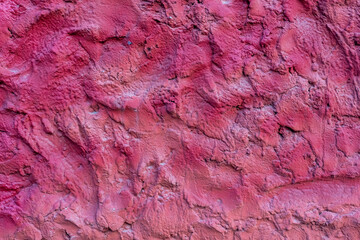 Close-up view of old textured magenta coloured rough plaster wall surface. Copy space for your text or decoration. Soft focus. Colorful construction material background theme.