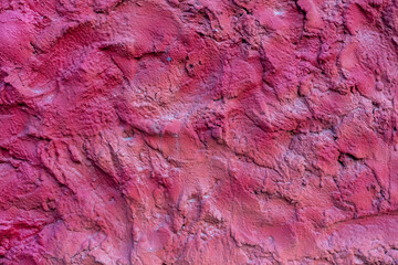 Close-up view of old textured magenta coloured rough plaster wall surface. Copy space for your text or decoration. Soft focus. Colorful construction material background theme.