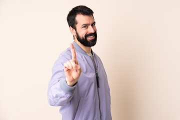 Caucasian man with beard wearing a jacket over isolated background showing and lifting a finger